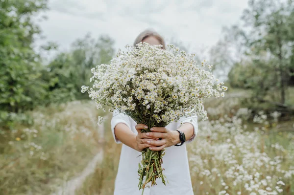 一个带着野花花束的女人把他的脸藏在花束后面 以保持自己的陌生 花卉中的选择性焦点 — 图库照片