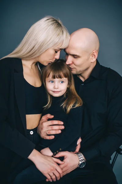 母親と父親は一緒に額に娘にキスをします スタジオポートレート — ストック写真