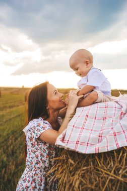 Anne ve bebek gün batımında samanlıkta oturup eğleniyorlar. Genç bir kadın ve küçük bir çocuk samanlıkta oturmuş hayatın tadını çıkarıyorlar..