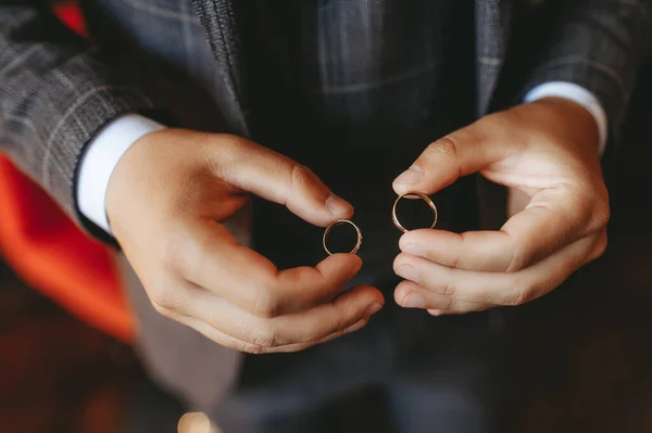 Groom holding in hands a gold rings. Closeup