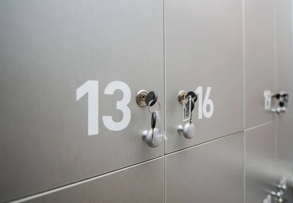 Gray metal cabinets gym with locks and numbers and keys. Numbers thirteen and sixteen. Closeup photo. Selective focus.