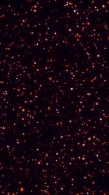 Yıldızlı gece gökyüzünün siyah zeminine dağılmış turuncu parlayan parçacıklar..