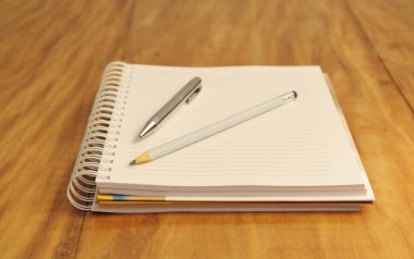 Kahverengi tahta masa zemininde kalem ve kalemle beyaz defter