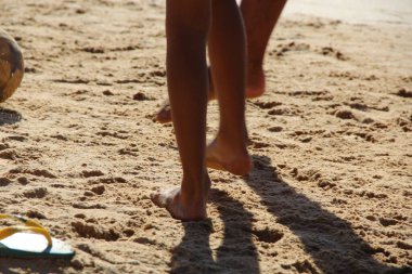 Kumsalda futbol oynayan insanların bacaklarına bakın. 