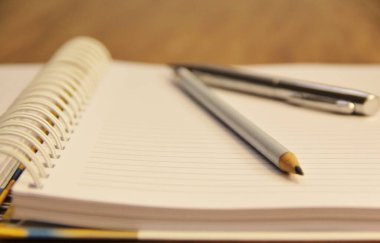Kahverengi tahta masa zemininde kalem ve kalemle beyaz defter