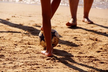 Kumsalda futbol oynayan insanların bacaklarına bakın. 