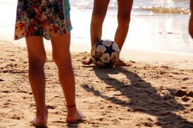 Kumsalda futbol oynayan insanların bacaklarına bakın. 