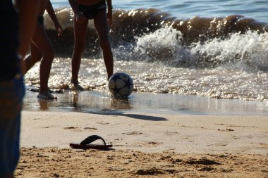 Kumsalda futbol oynayan insanların bacaklarına bakın. 