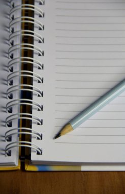 Kahverengi tahta masa zemininde beyaz defter kalemi