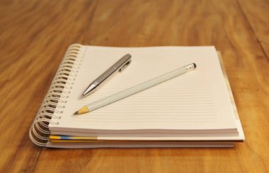 Kahverengi tahta masa zemininde kalem ve kalemle beyaz defter