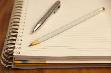 Kahverengi tahta masa zemininde kalem ve kalemle beyaz defter