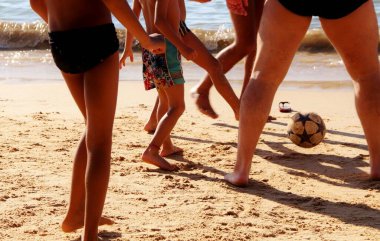 Kumsalda futbol oynayan insanların bacaklarına bakın. 