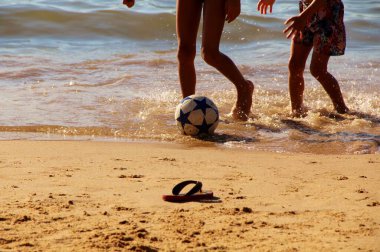 Kumsalda futbol oynayan insanların bacaklarına bakın. 