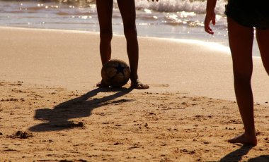 Kumsalda futbol oynayan insanların bacaklarına bakın. 