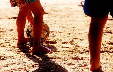 Kumsalda futbol oynayan insanların bacaklarına bakın. 