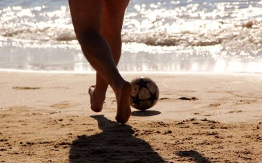 Kumsalda futbol oynayan insanların bacaklarına bakın. 