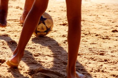 Kumsalda futbol oynayan insanların bacaklarına bakın. 