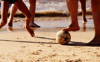 Kumsalda futbol oynayan insanların bacaklarına bakın. 