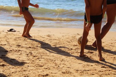 Kumsalda futbol oynayan insanların bacaklarına bakın. 