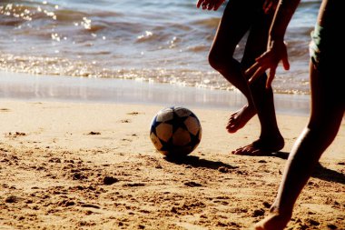 Kumsalda futbol oynayan insanların bacaklarına bakın. 