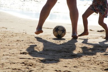 Kumsalda futbol oynayan insanların bacaklarına bakın. 