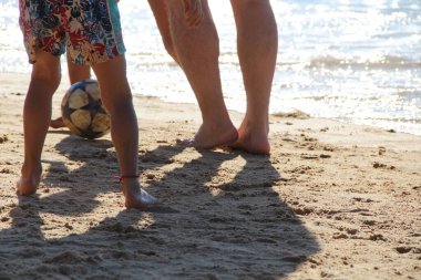 Kumsalda futbol oynayan insanların bacaklarına bakın. 