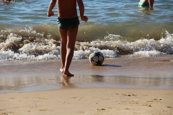 Kumsalda futbol oynayan insanların bacaklarına bakın. 