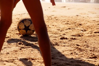 Kumsalda futbol oynayan insanların bacaklarına bakın. 