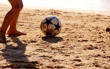 Kumsalda futbol oynayan insanların bacaklarına bakın. 