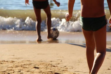 Kumsalda futbol oynayan insanların bacaklarına bakın. 