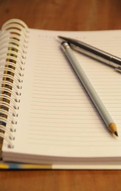 Kahverengi tahta masa zemininde kalem ve kalemle beyaz defter