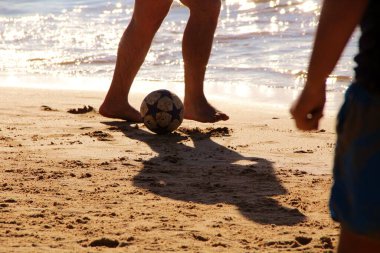 Kumsalda futbol oynayan insanların bacaklarına bakın. 