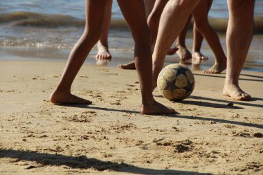 Kumsalda futbol oynayan insanların bacaklarına bakın. 