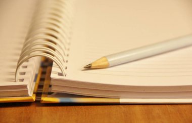 Kahverengi tahta masa zemininde beyaz defter kalemi