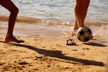 Kumsalda futbol oynayan insanların bacaklarına bakın. 