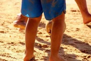 Kumsalda futbol oynayan insanların bacaklarına bakın. 