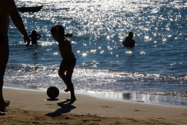 Futbol oynayan, yüzen ve kumsalda dinlenen insanları izleyin. 