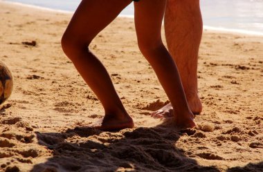 Kumsalda futbol oynayan insanların bacaklarına bakın. 