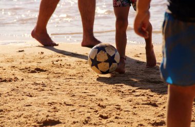Kumsalda futbol oynayan insanların bacaklarına bakın. 