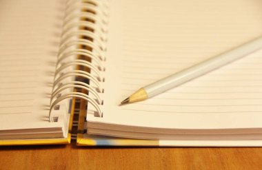 Kahverengi tahta masa zemininde beyaz defter kalemi