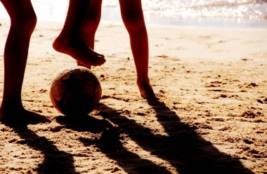 Kumsalda futbol oynayan insanların bacaklarına bakın. 