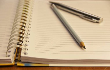 Kahverengi tahta masa zemininde kalem ve kalemle beyaz defter