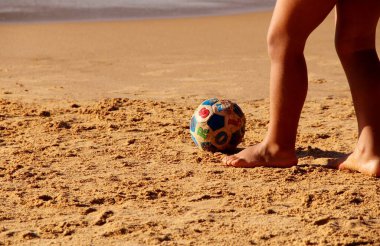 Kumsalda futbol oynayan insanların bacaklarına bakın. 