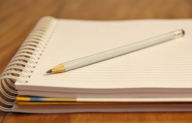 Kahverengi ahşap masa zemininde kurşun kalemli beyaz defter