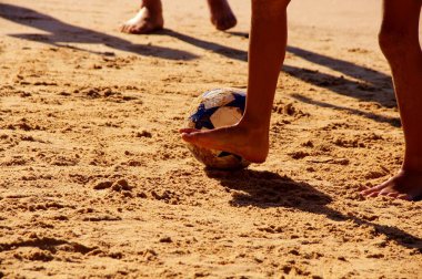 Kumsalda futbol oynayan insanların bacaklarına bakın. 