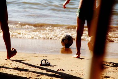 Kumsalda futbol oynayan insanların bacaklarına bakın. 