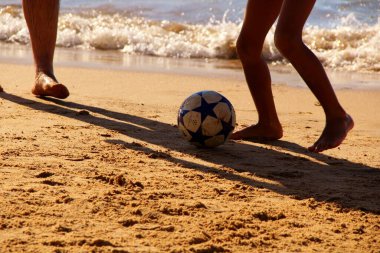 Kumsalda futbol oynayan insanların bacaklarına bakın. 