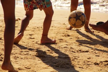 Kumsalda futbol oynayan insanların bacaklarına bakın. 