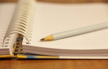 Kahverengi tahta masa zemininde beyaz defter kalemi