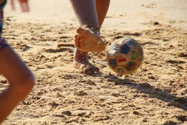 Kumsalda futbol oynayan insanların bacaklarına bakın. 